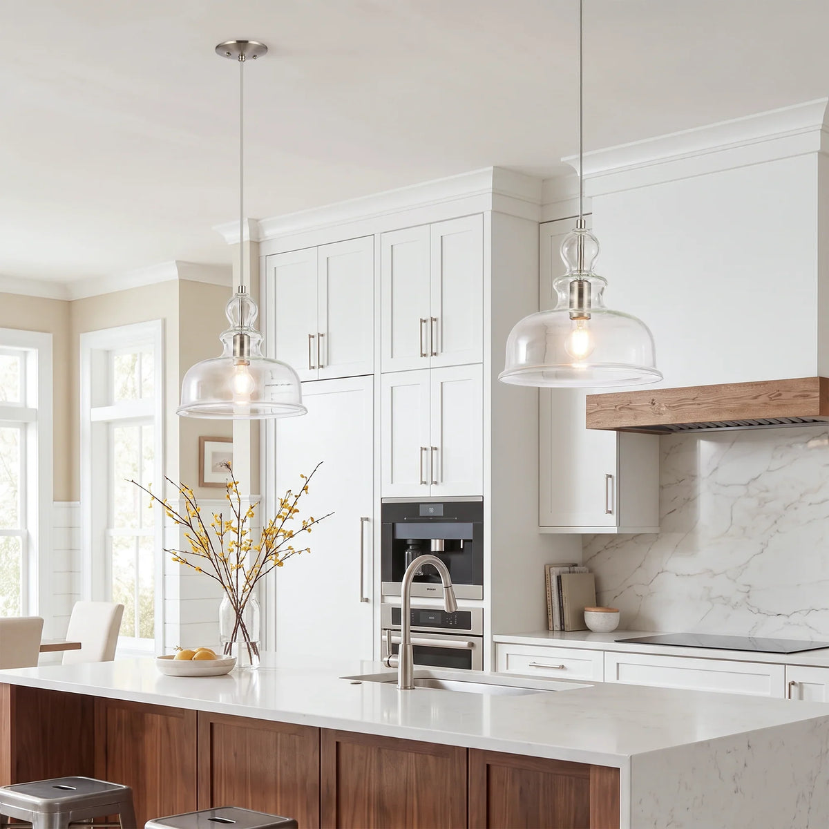 Two glass pendant light fixtures hanging over a white marble kitchen island