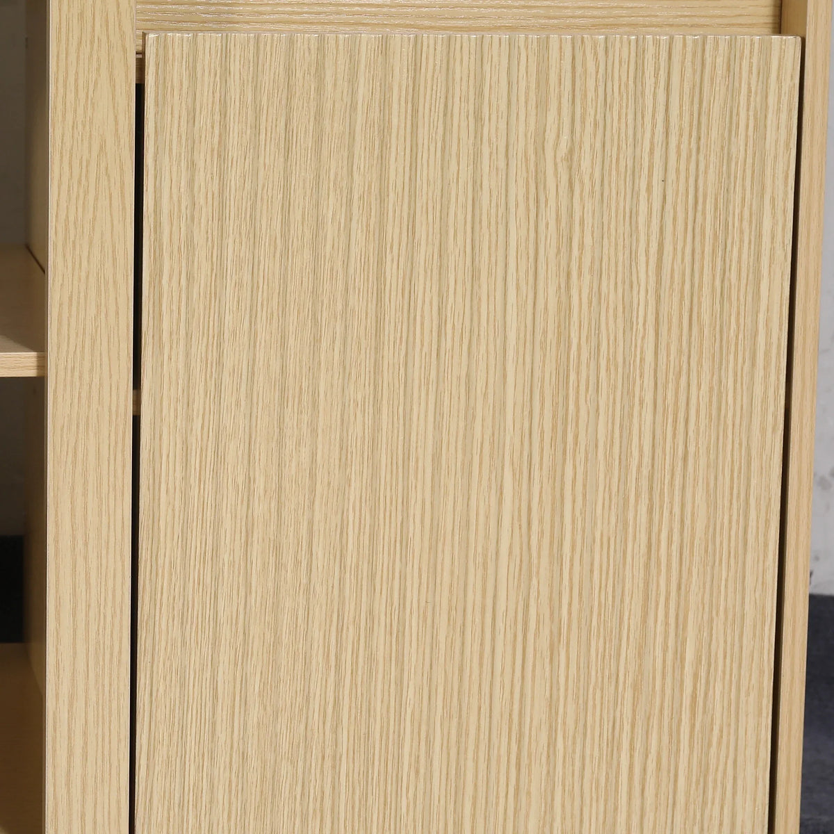 Close-up of a light-toned oak wood cabinet door with vertical grain.