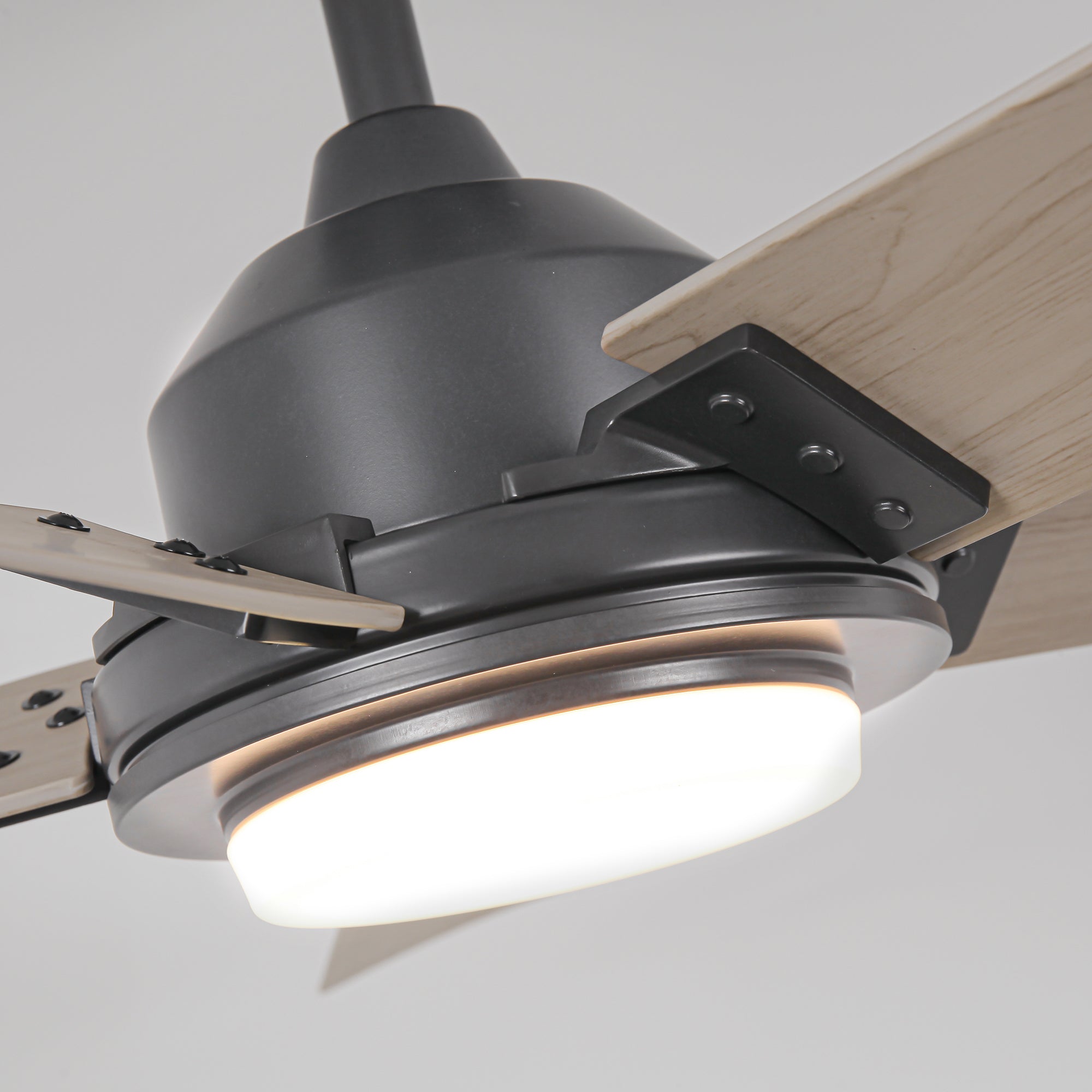Close-up of a modern matte black ceiling fan with light wood blades and an integrated light.