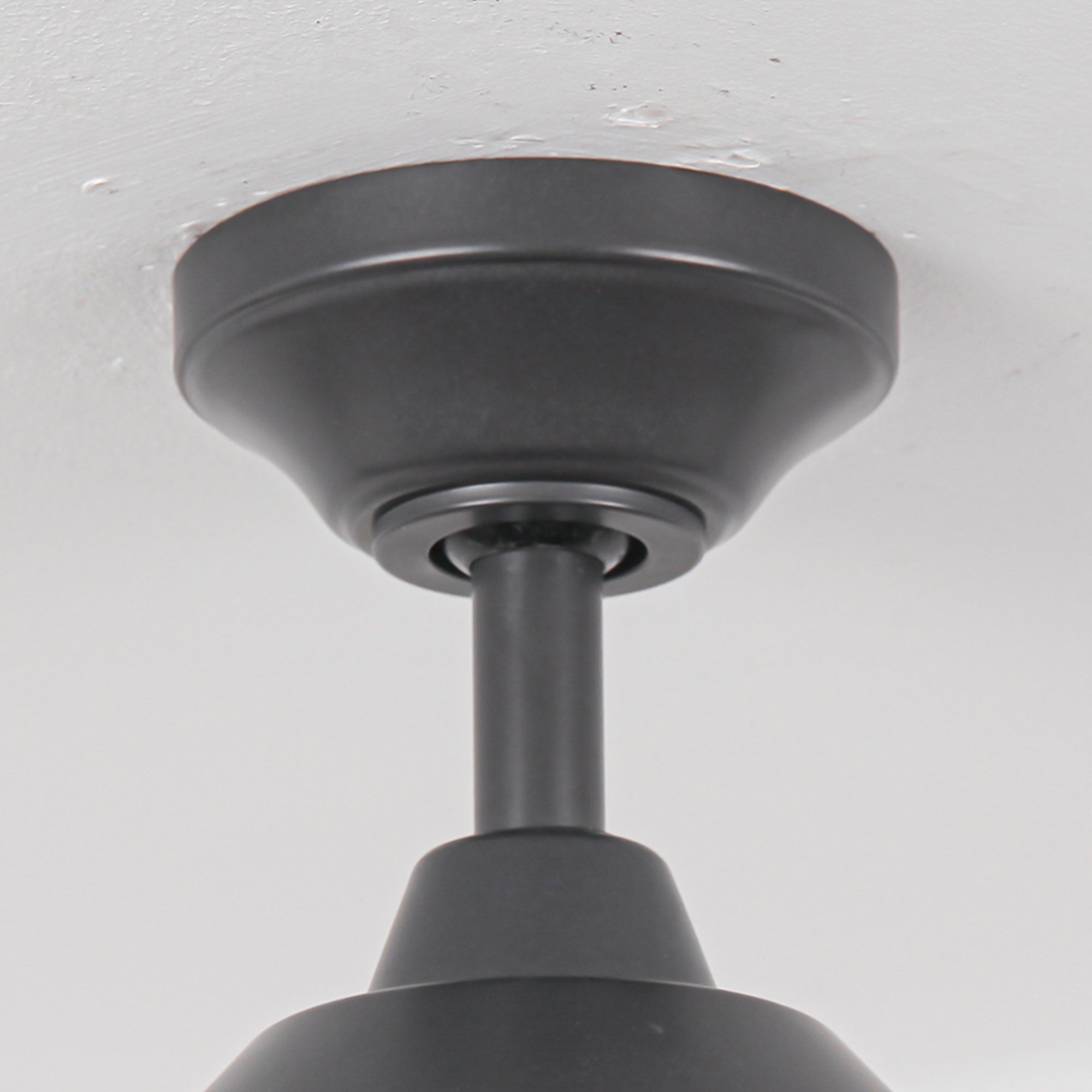 Close-up of a matte black ceiling fan mounting bracket and downrod