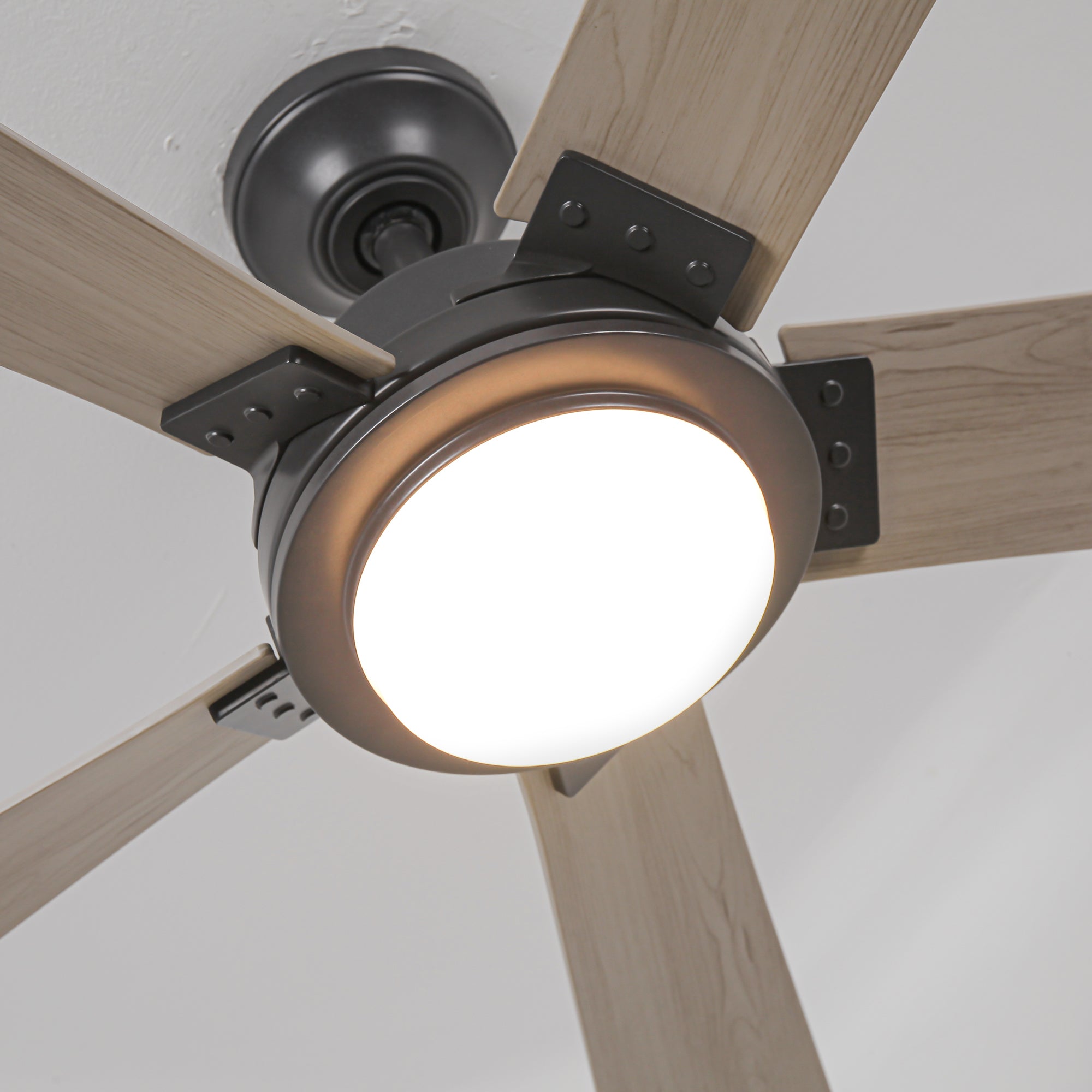 Close-up of a modern ceiling fan with light wood blades and an integrated light fixture.