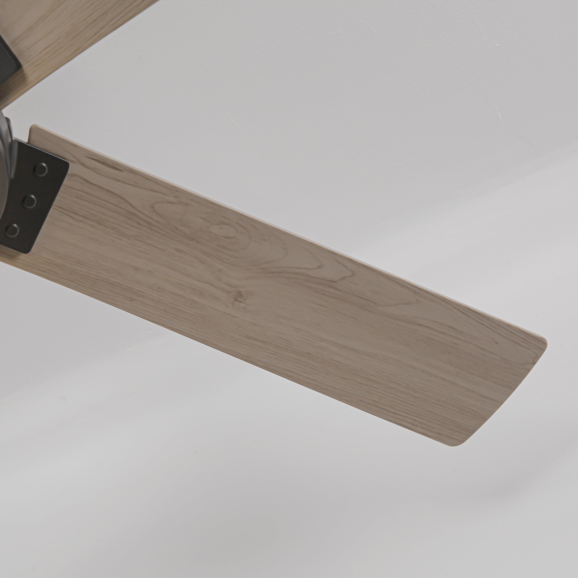 Close-up of a modern ceiling fan blade with a light wood grain finish.