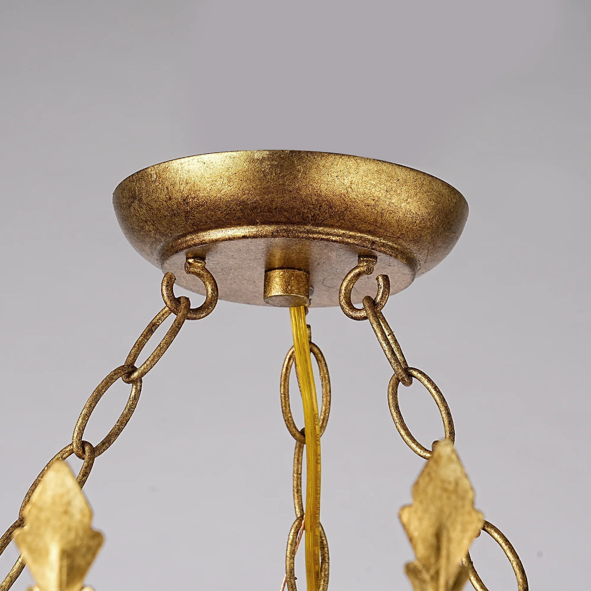 Close-up of a gold-finished ceiling fan canopy with decorative chains