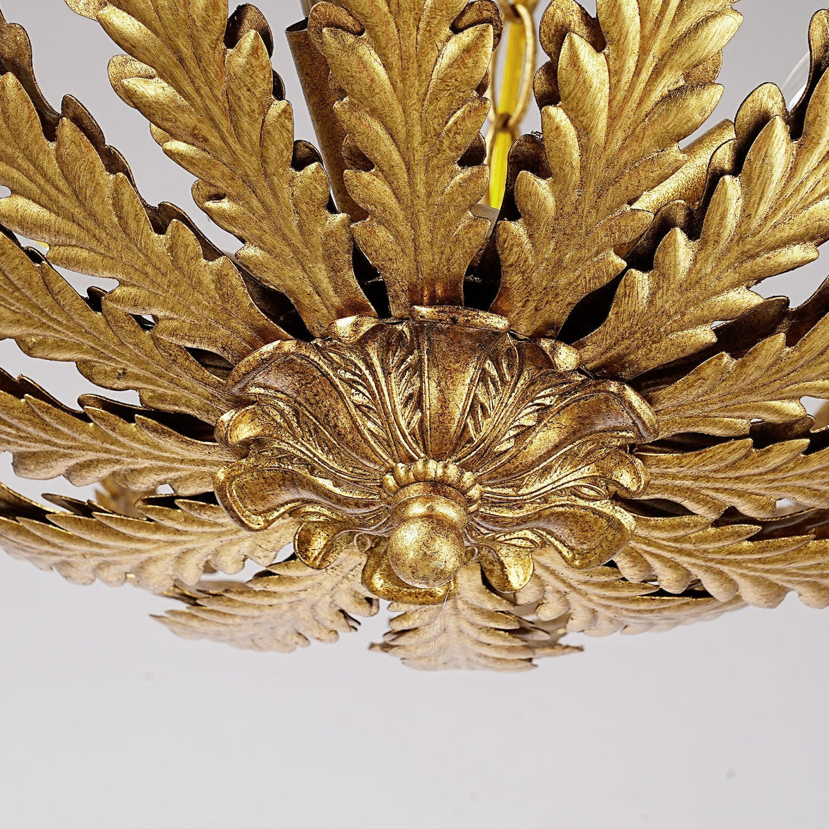 Close-up of an ornate gold-finished ceiling fan canopy with acanthus leaf details.