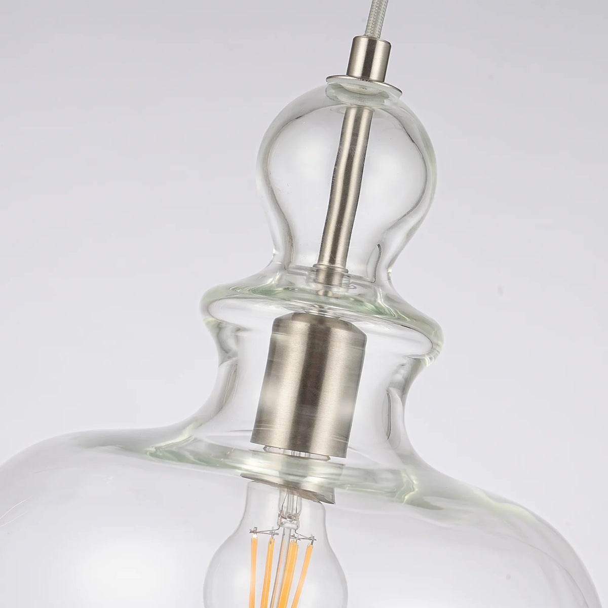 Close-up of a modern glass pendant light fixture with a brushed metal socket